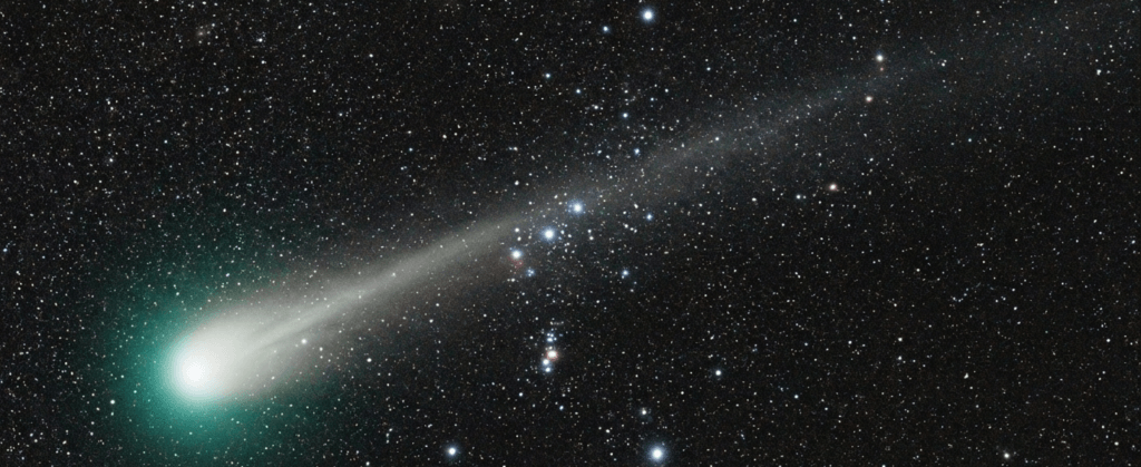 A realistic view of Comet C/2025 R3 at peak brightness in 2026, showing its glowing coma and long tail in the night sky